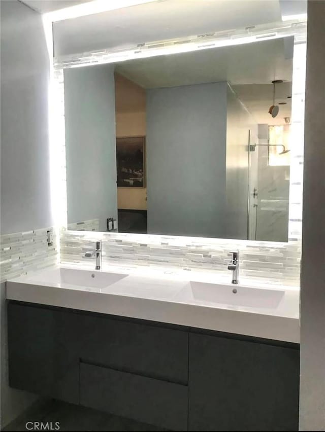 full bath featuring a sink, backsplash, double vanity, and a walk in shower