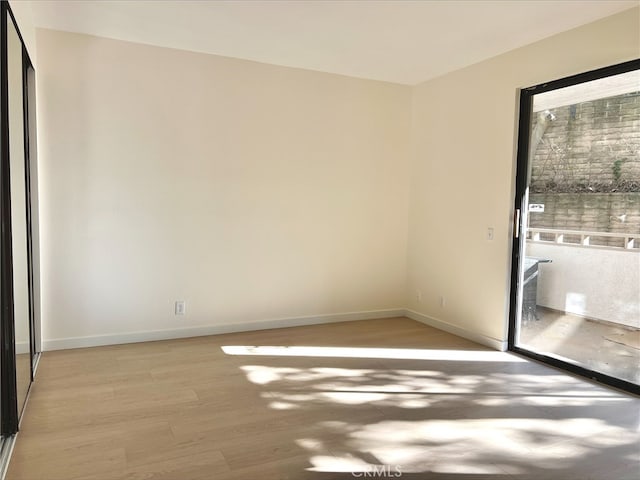 spare room with baseboards and light wood-style flooring