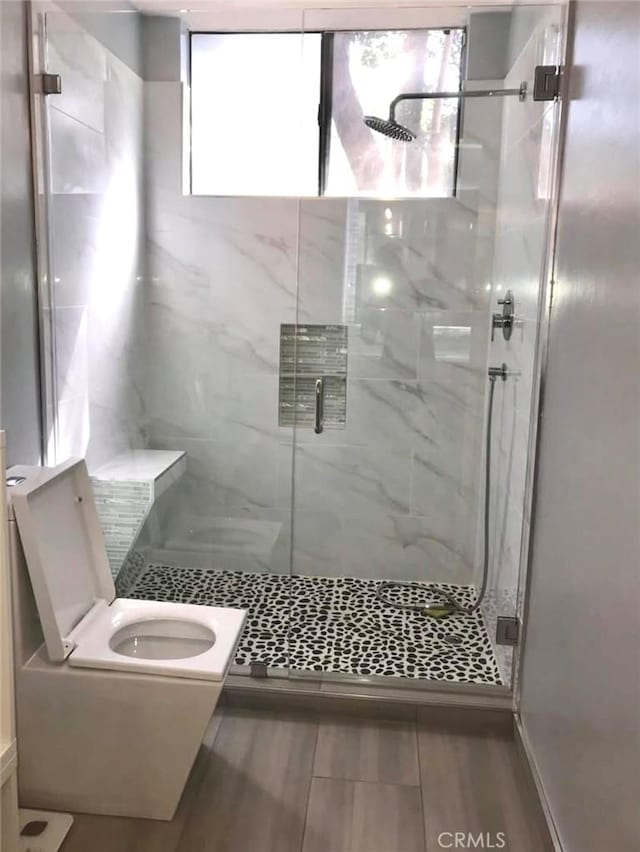 full bath featuring a marble finish shower and toilet