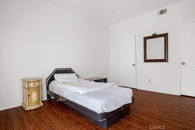 bedroom with visible vents, baseboards, and wood finished floors