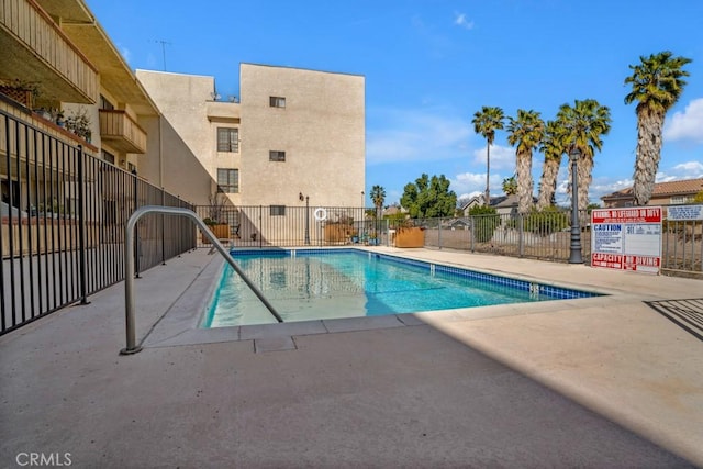 community pool with a patio and fence