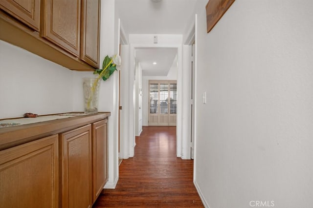 corridor featuring dark wood-style floors and baseboards