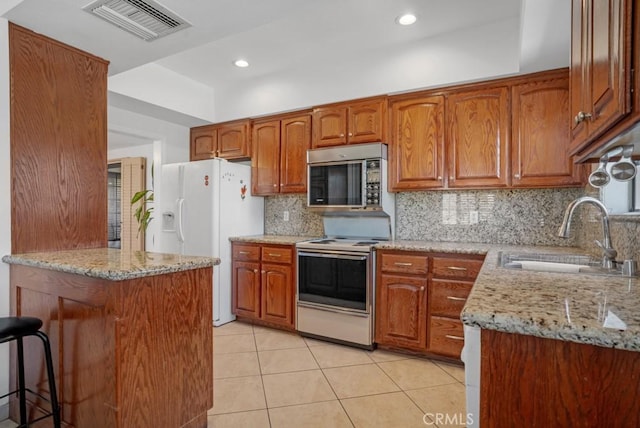 kitchen featuring visible vents, a sink, electric stove, white refrigerator with ice dispenser, and stainless steel microwave