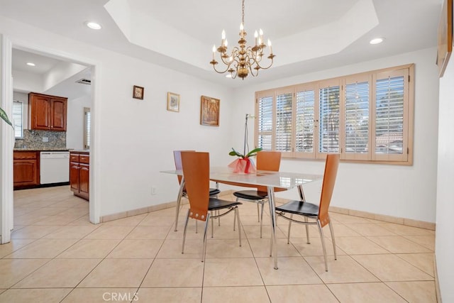 dining space featuring a tray ceiling, light tile patterned floors, and baseboards