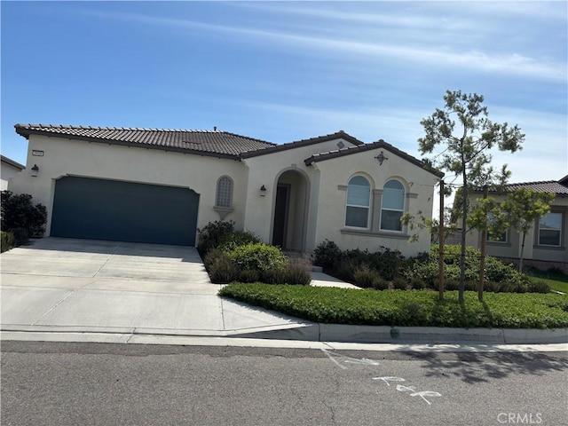 mediterranean / spanish-style home with a tiled roof, an attached garage, driveway, and stucco siding