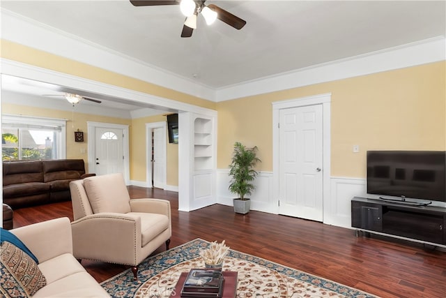 living area with wood finished floors, built in features, a ceiling fan, and wainscoting