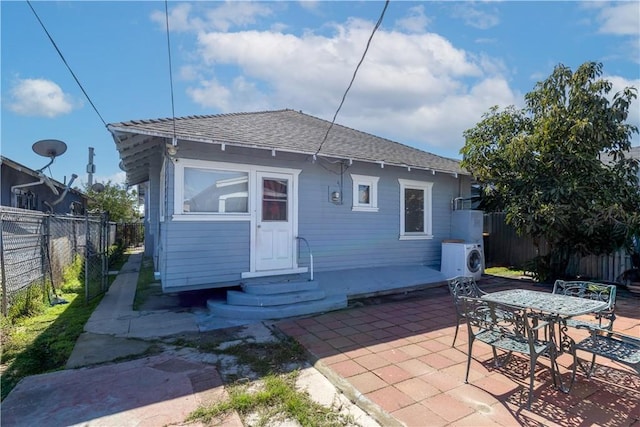 back of property with ac unit, entry steps, a fenced backyard, roof with shingles, and a patio area