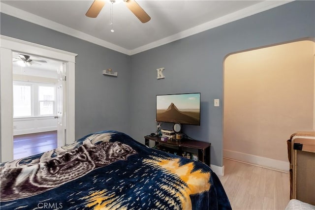 bedroom featuring a ceiling fan, wood finished floors, baseboards, and ornamental molding