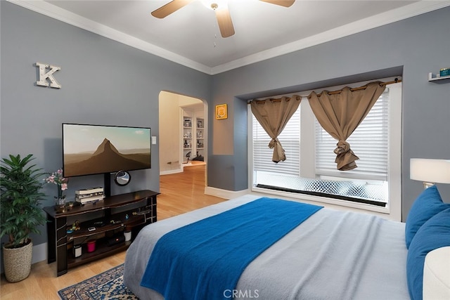 bedroom featuring ceiling fan, arched walkways, wood finished floors, and crown molding