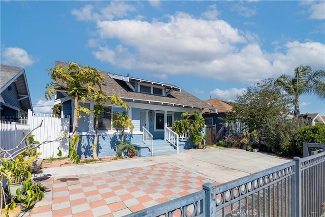 back of property featuring roof mounted solar panels, roof with shingles, a porch, and fence