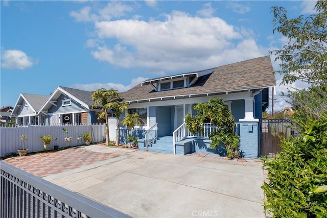 back of property featuring a fenced front yard, covered porch, and roof with shingles