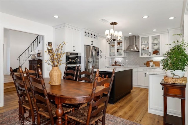 dining area with recessed lighting, a notable chandelier, light wood-style flooring, and stairs