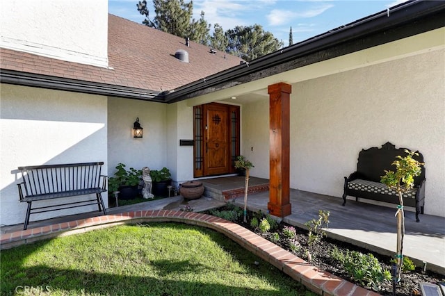 doorway to property featuring stucco siding and roof with shingles