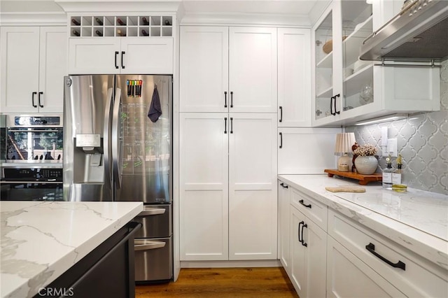 kitchen with under cabinet range hood, stainless steel appliances, wood finished floors, and white cabinets