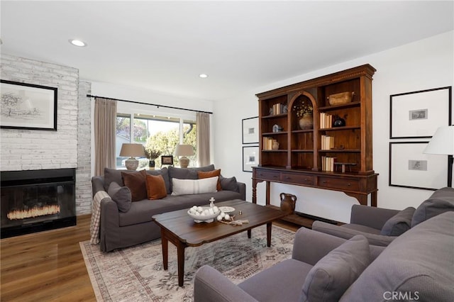 living area featuring a brick fireplace, recessed lighting, and light wood finished floors