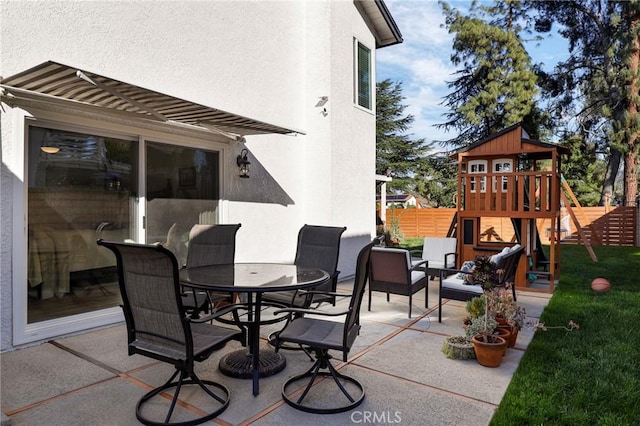 view of patio / terrace featuring outdoor dining area, fence, and a playground