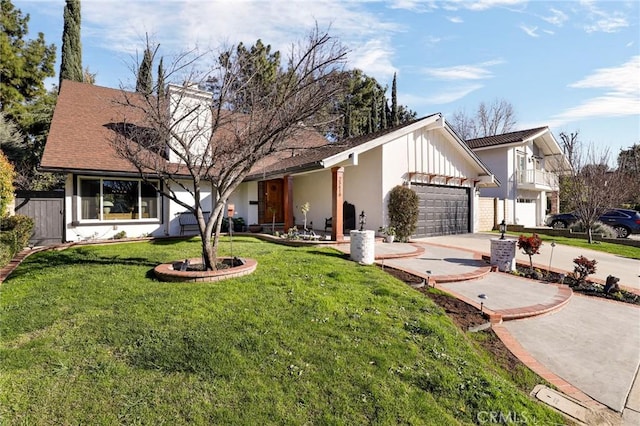 view of front facade with fence, concrete driveway, a front yard, a chimney, and a garage