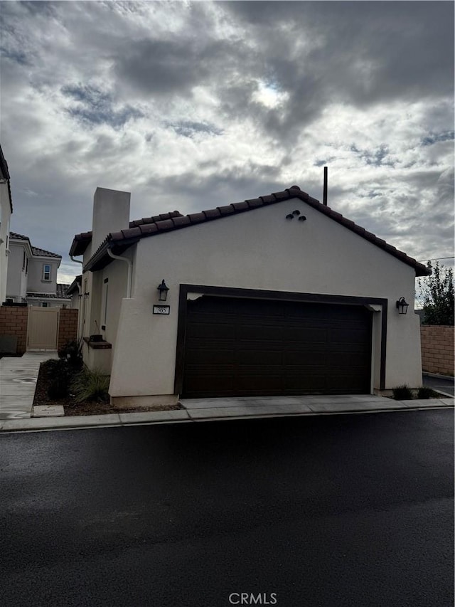 view of front of home with a tiled roof, fence, and stucco siding