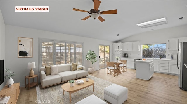 living area with lofted ceiling, light wood-style flooring, ceiling fan with notable chandelier, and visible vents