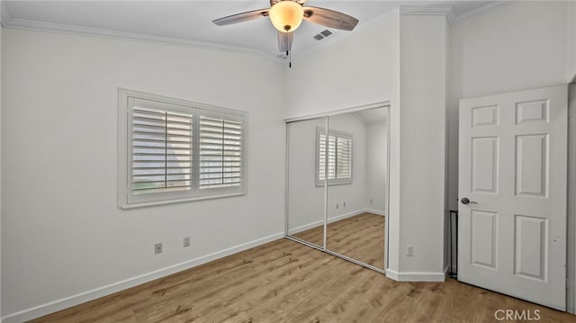 unfurnished bedroom with visible vents, crown molding, baseboards, light wood-type flooring, and a closet