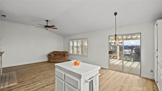 interior space with ceiling fan with notable chandelier, light wood-type flooring, baseboards, and vaulted ceiling