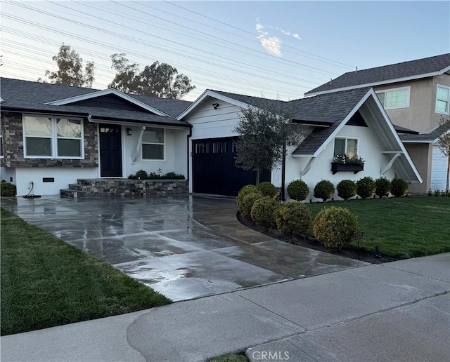 view of front of house with an attached garage, roof with shingles, concrete driveway, and a front lawn