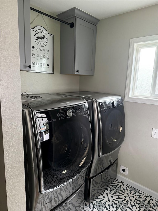 clothes washing area featuring baseboards, cabinet space, and independent washer and dryer