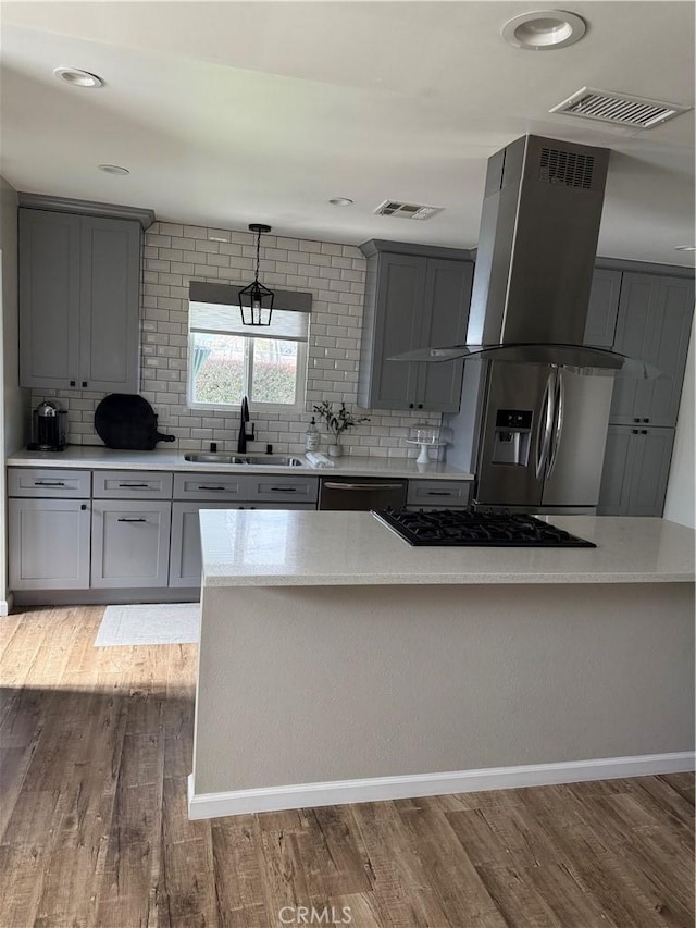 kitchen featuring island range hood, visible vents, gray cabinets, and a sink