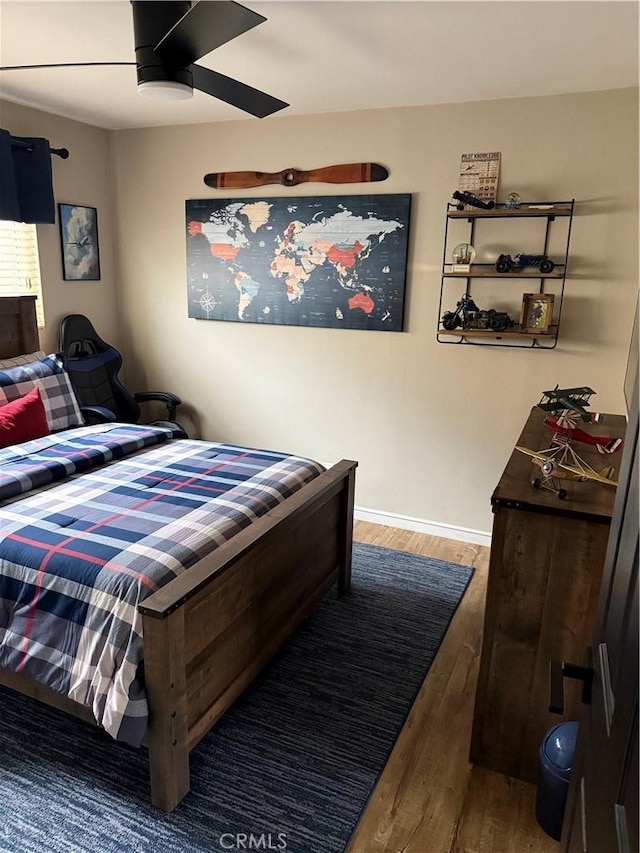 bedroom featuring ceiling fan, baseboards, and wood finished floors