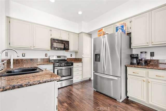 kitchen with a sink, dark stone counters, recessed lighting, appliances with stainless steel finishes, and dark wood-style flooring