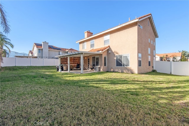 back of house with a yard, a patio area, a fenced backyard, and stucco siding