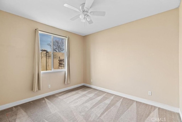 carpeted spare room with a ceiling fan and baseboards