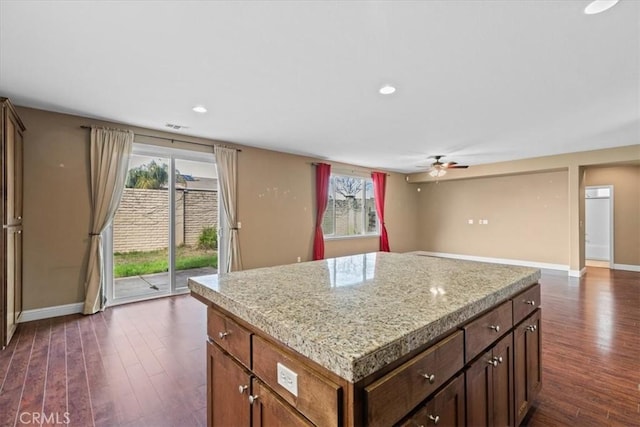 kitchen with dark wood-type flooring, plenty of natural light, a ceiling fan, and a center island