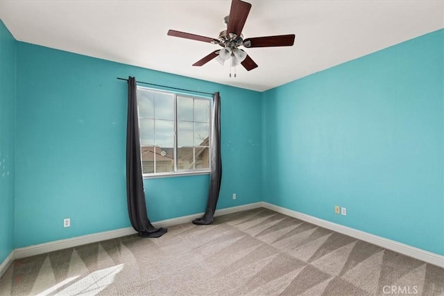 carpeted empty room featuring a ceiling fan and baseboards