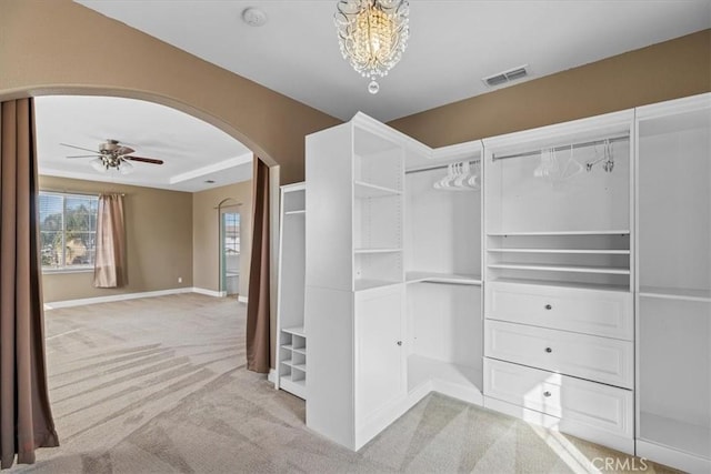 spacious closet with arched walkways, visible vents, ceiling fan, and carpet floors