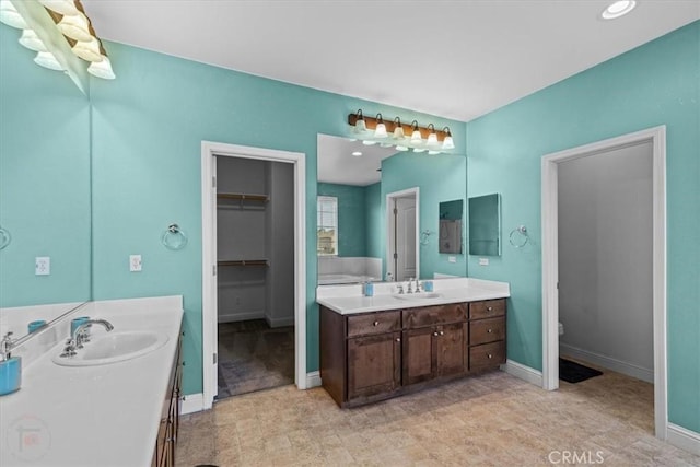 full bathroom with toilet, two vanities, baseboards, and a sink