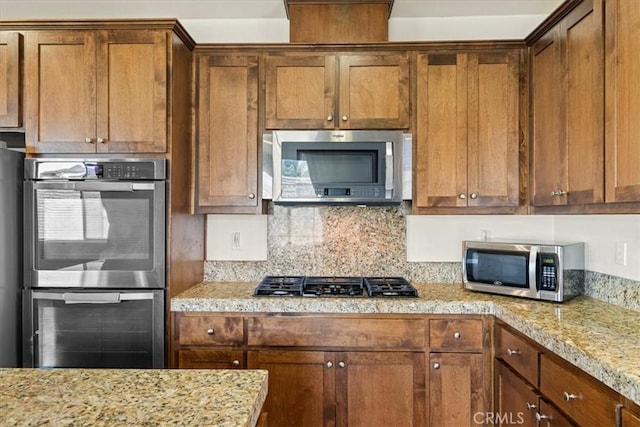 kitchen with decorative backsplash, brown cabinetry, and appliances with stainless steel finishes