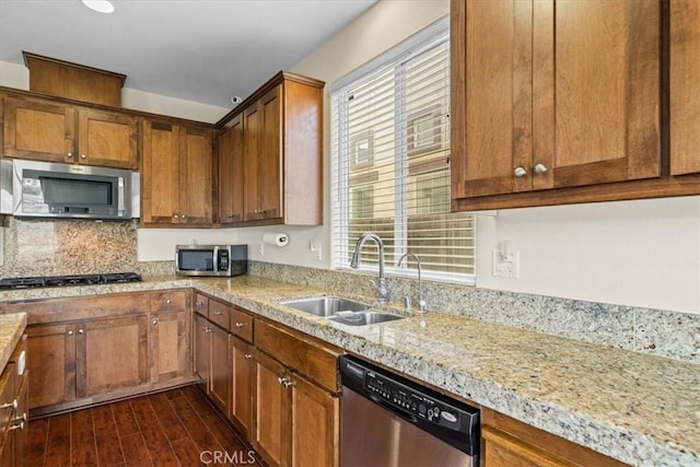 kitchen with a sink, stainless steel appliances, brown cabinets, and dark wood-type flooring