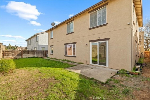 back of house featuring stucco siding, a lawn, a fenced backyard, and a patio area