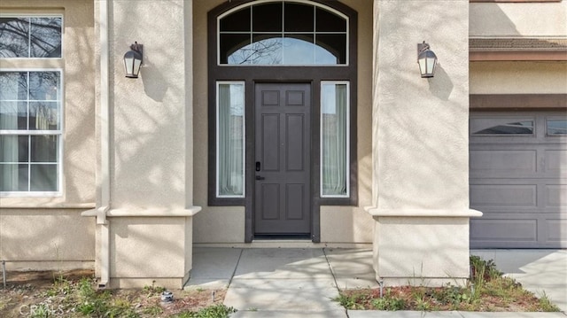 property entrance with a garage and stucco siding