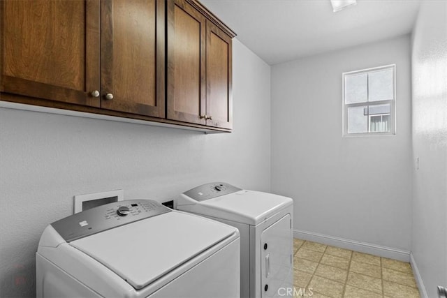 washroom with washer and clothes dryer, cabinet space, baseboards, and light floors