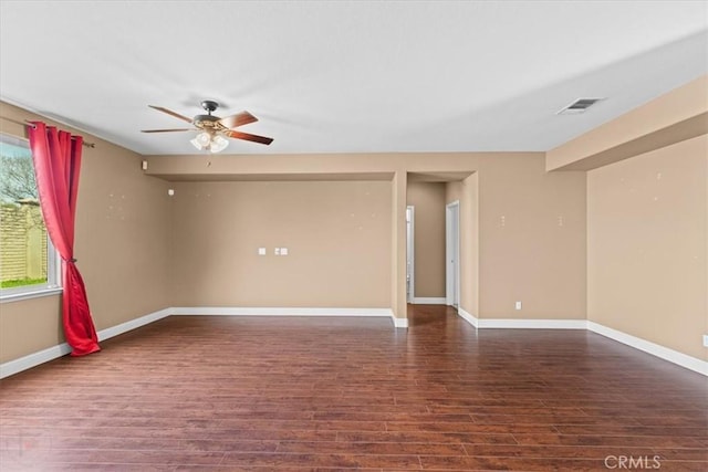 unfurnished room with visible vents, a healthy amount of sunlight, dark wood finished floors, and a ceiling fan