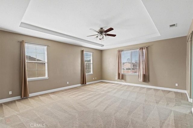empty room featuring a tray ceiling, baseboards, and carpet floors