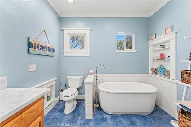 full bath featuring tile patterned flooring, crown molding, a wainscoted wall, toilet, and a freestanding bath