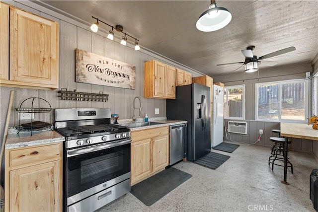 kitchen with a ceiling fan, light brown cabinetry, a sink, a wall unit AC, and appliances with stainless steel finishes