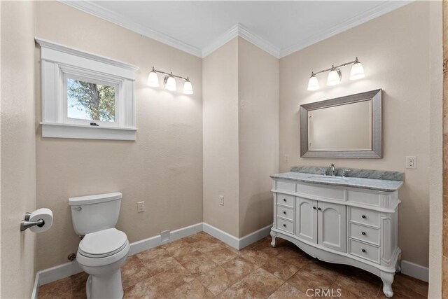 bathroom with vanity, toilet, crown molding, and baseboards