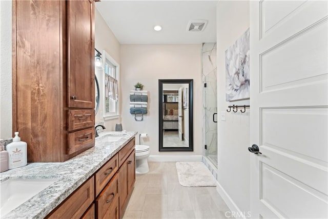 bathroom featuring visible vents, toilet, a sink, a shower stall, and double vanity