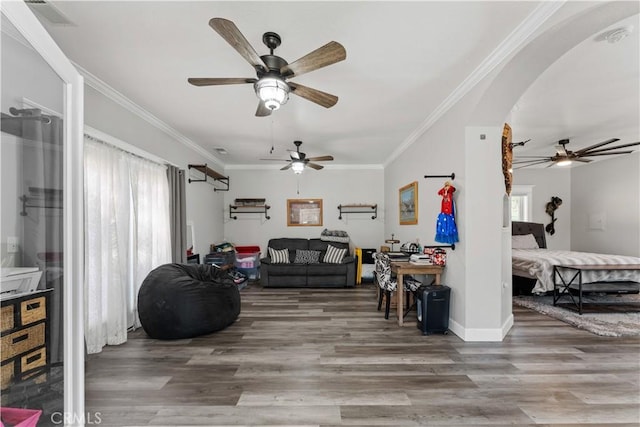 living room featuring baseboards, arched walkways, wood finished floors, and crown molding