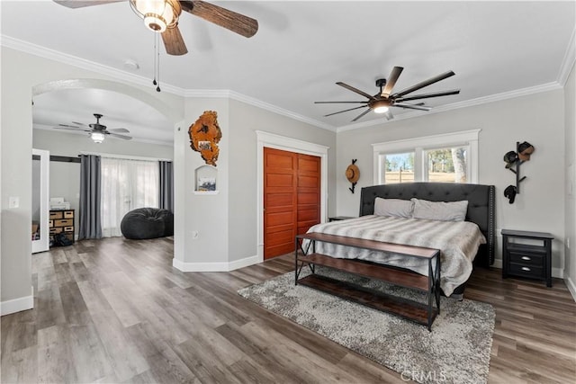 bedroom with wood finished floors, arched walkways, and ornamental molding