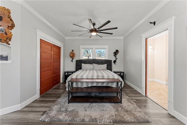 bedroom with a closet, crown molding, baseboards, and wood finished floors